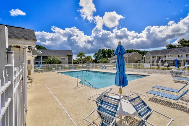 community pool featuring a residential view, fence, and a patio