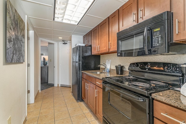 kitchen with stone counters, light tile patterned floors, sink, and black appliances