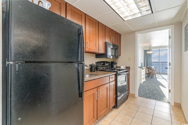 kitchen featuring light tile patterned floors, black appliances, and a paneled ceiling