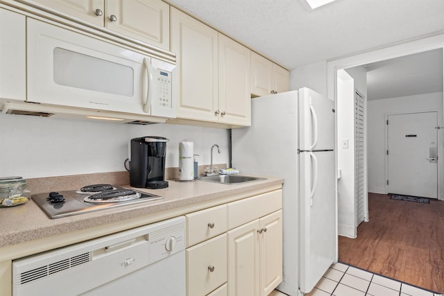 kitchen with white appliances, light countertops, a sink, and light tile patterned flooring