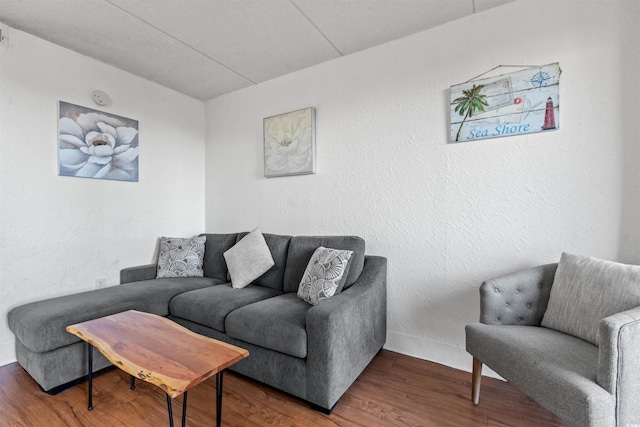 living area with baseboards, wood finished floors, and a textured wall