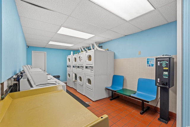 common laundry area featuring stacked washer / dryer, wainscoting, tile walls, and separate washer and dryer