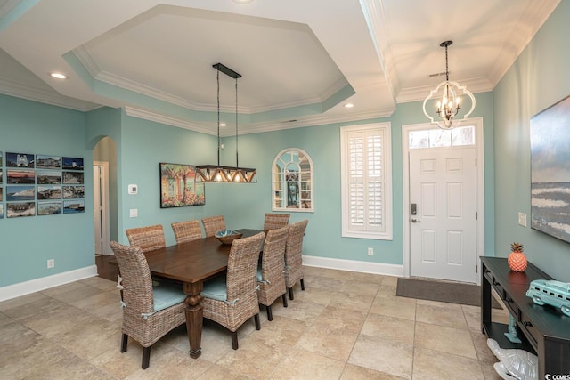 dining space with crown molding, a tray ceiling, and a chandelier