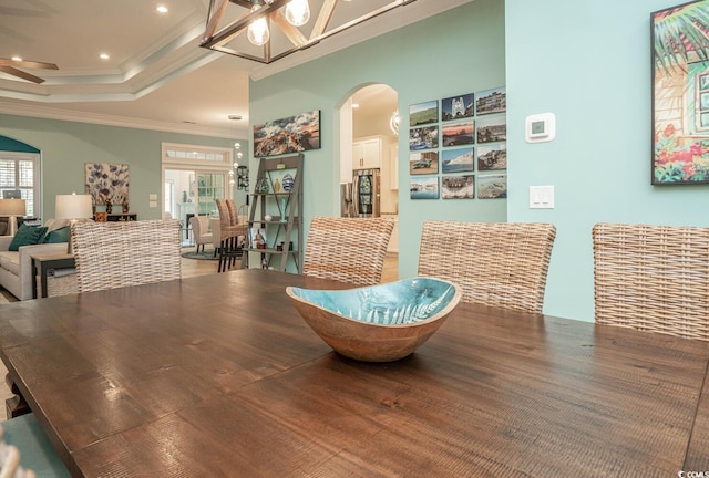 dining room featuring ceiling fan with notable chandelier, a tray ceiling, and crown molding