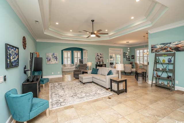 living room with ceiling fan, a tray ceiling, and crown molding