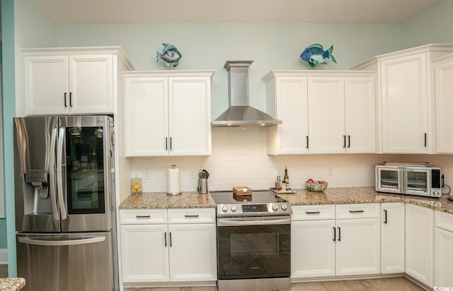 kitchen with appliances with stainless steel finishes, wall chimney exhaust hood, backsplash, and light stone counters