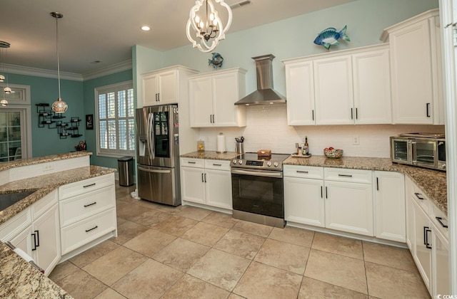 kitchen featuring decorative light fixtures, appliances with stainless steel finishes, wall chimney range hood, and white cabinetry