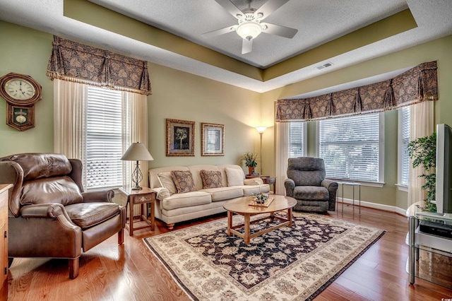 living room featuring ceiling fan, hardwood / wood-style floors, and a raised ceiling