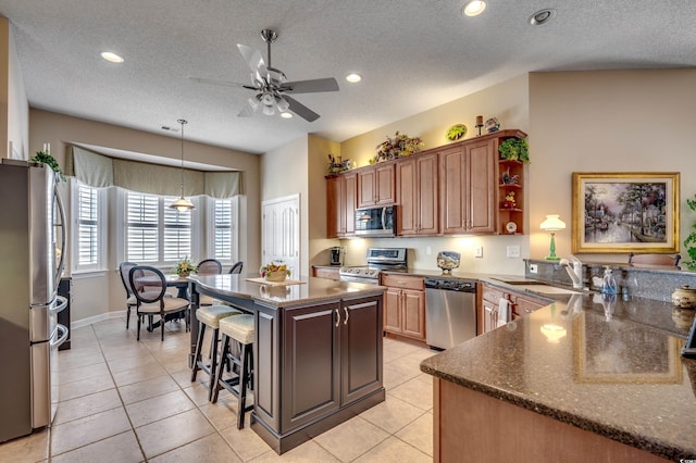 kitchen with sink, a textured ceiling, appliances with stainless steel finishes, and a center island