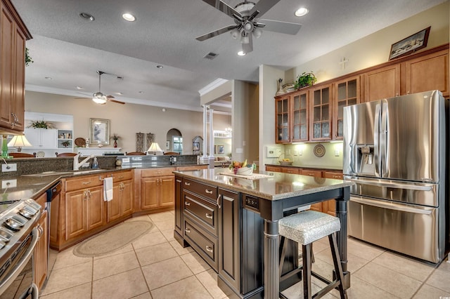 kitchen with a center island, a kitchen breakfast bar, a textured ceiling, stainless steel appliances, and light tile patterned floors