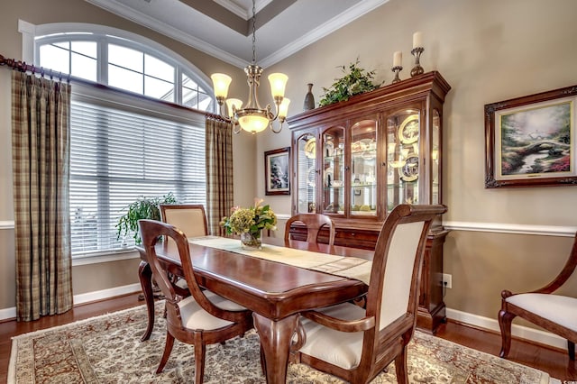 dining room with dark hardwood / wood-style flooring, crown molding, and an inviting chandelier