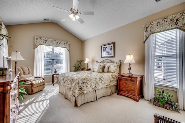 carpeted bedroom with ceiling fan, vaulted ceiling, multiple windows, and a textured ceiling