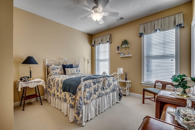 bedroom with ceiling fan, multiple windows, a textured ceiling, and carpet flooring