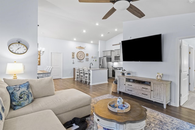 living room featuring lofted ceiling, dark hardwood / wood-style flooring, sink, and ceiling fan with notable chandelier