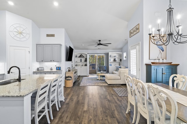 dining area with dark wood-type flooring, ceiling fan with notable chandelier, and sink