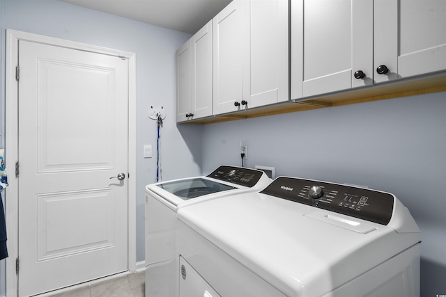 clothes washing area featuring cabinets and washer and dryer