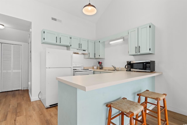 kitchen featuring high vaulted ceiling, sink, kitchen peninsula, and white appliances