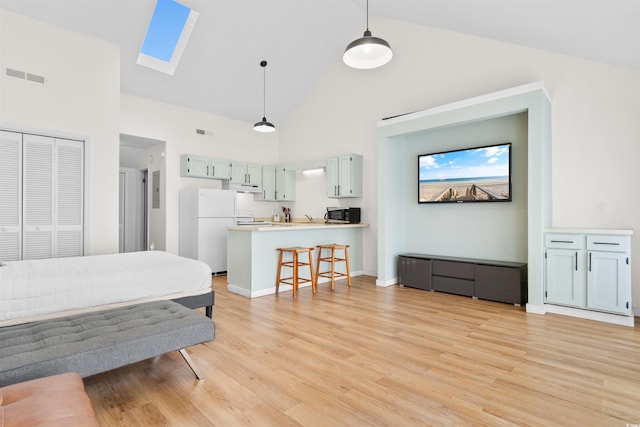 living room featuring a skylight, sink, light hardwood / wood-style floors, and high vaulted ceiling