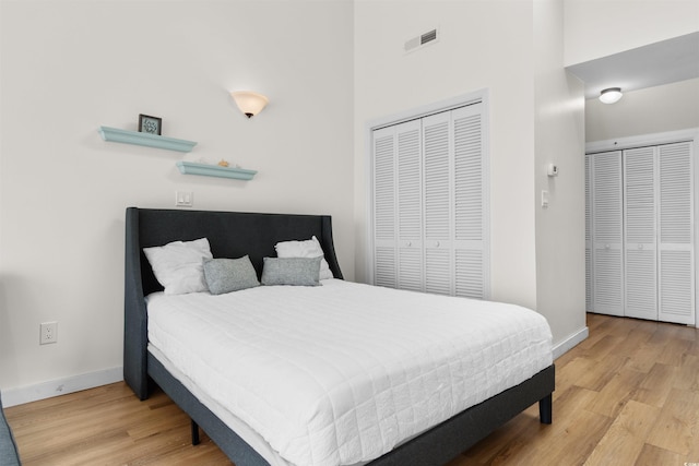 bedroom featuring light hardwood / wood-style floors and a high ceiling