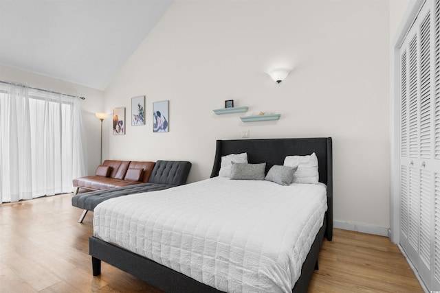 bedroom with a closet, lofted ceiling, and light wood-type flooring