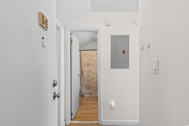 corridor featuring vaulted ceiling, electric panel, a textured ceiling, and hardwood / wood-style floors