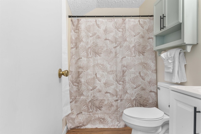 bathroom with curtained shower, a textured ceiling, toilet, and vanity