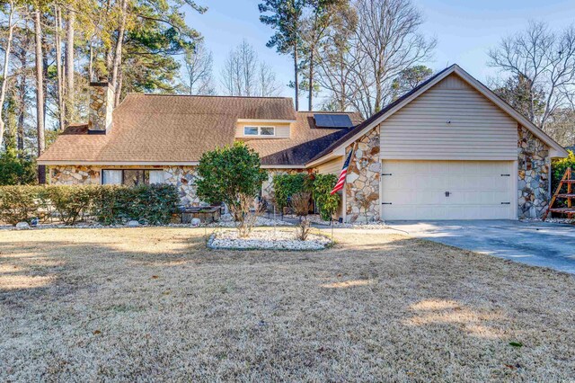 view of front of property featuring a garage, a front yard, and solar panels