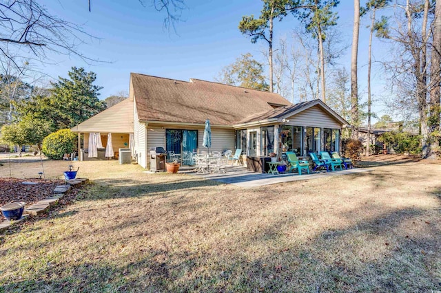 rear view of property featuring a patio, a sunroom, a yard, and cooling unit