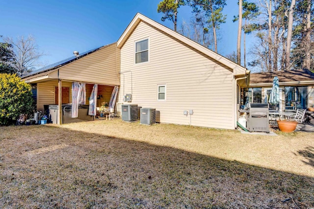 rear view of house featuring central AC unit and a yard