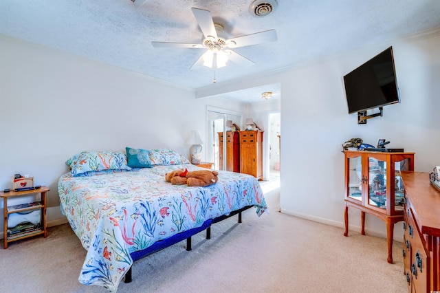 carpeted bedroom with a textured ceiling, ornamental molding, a closet, and ceiling fan