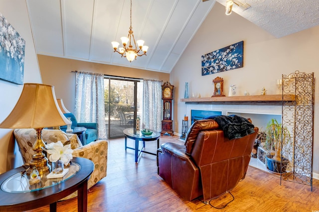 living room with an inviting chandelier, hardwood / wood-style floors, high vaulted ceiling, and a textured ceiling