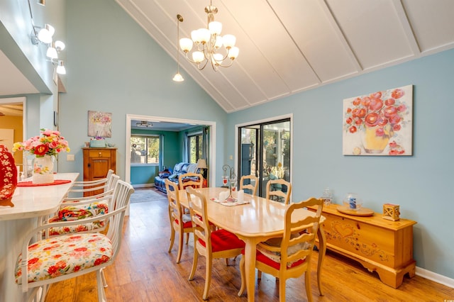 dining space featuring a chandelier, high vaulted ceiling, and light hardwood / wood-style flooring