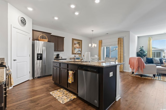 kitchen featuring appliances with stainless steel finishes, decorative light fixtures, a kitchen island with sink, dark brown cabinetry, and sink