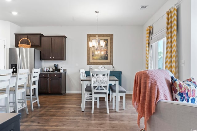 dining area with dark hardwood / wood-style flooring and an inviting chandelier