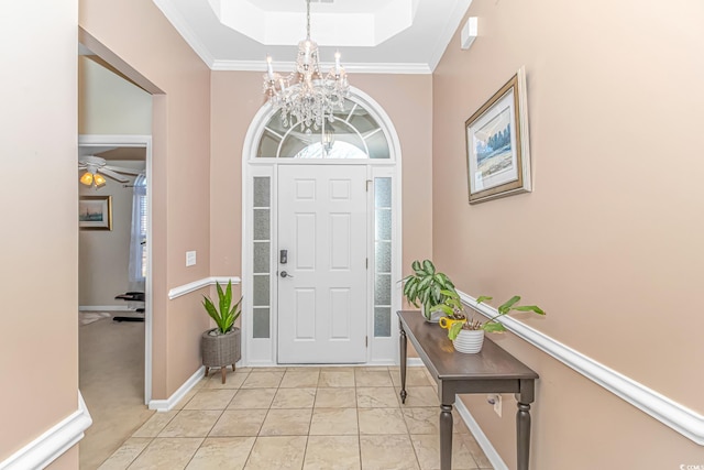 entryway with light colored carpet, crown molding, ceiling fan with notable chandelier, and a raised ceiling