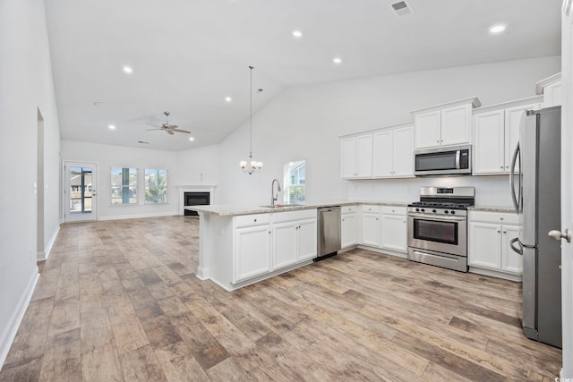 kitchen with appliances with stainless steel finishes, white cabinetry, tasteful backsplash, sink, and hanging light fixtures