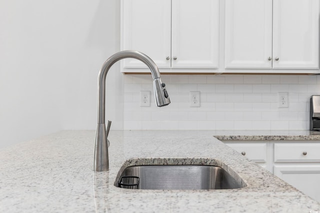 details with white cabinets, decorative backsplash, and light stone countertops