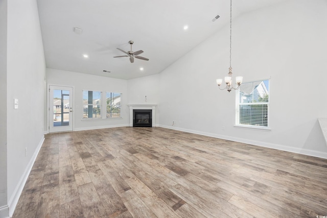 unfurnished living room featuring ceiling fan with notable chandelier, hardwood / wood-style floors, and high vaulted ceiling