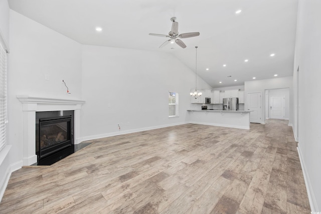 unfurnished living room with ceiling fan, high vaulted ceiling, and light wood-type flooring