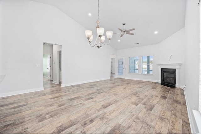 unfurnished living room with high vaulted ceiling, light wood-type flooring, and ceiling fan with notable chandelier