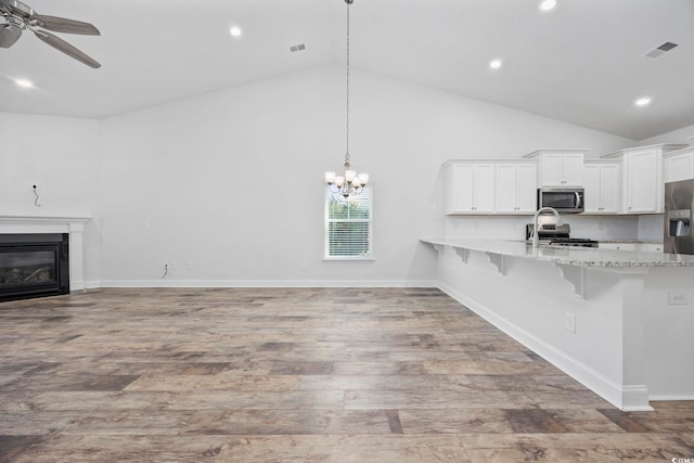 kitchen featuring appliances with stainless steel finishes, white cabinetry, tasteful backsplash, hanging light fixtures, and a breakfast bar