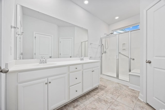 bathroom featuring a shower with shower door and vanity