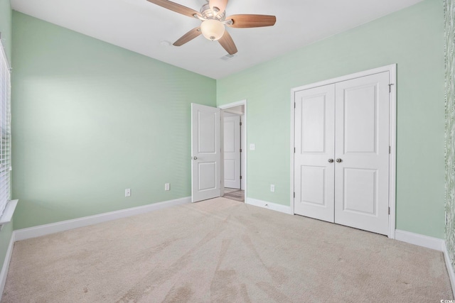 unfurnished bedroom featuring ceiling fan, a closet, and light carpet