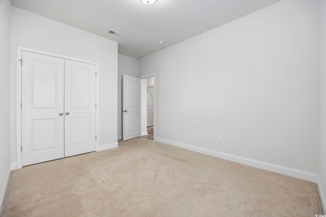 unfurnished bedroom with light carpet and a closet