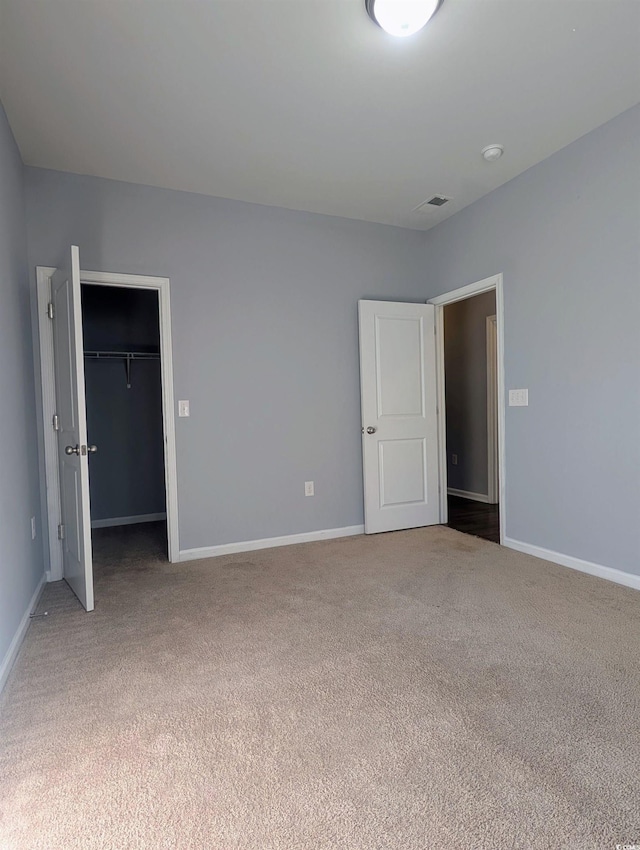 unfurnished bedroom featuring a spacious closet, a closet, and carpet floors