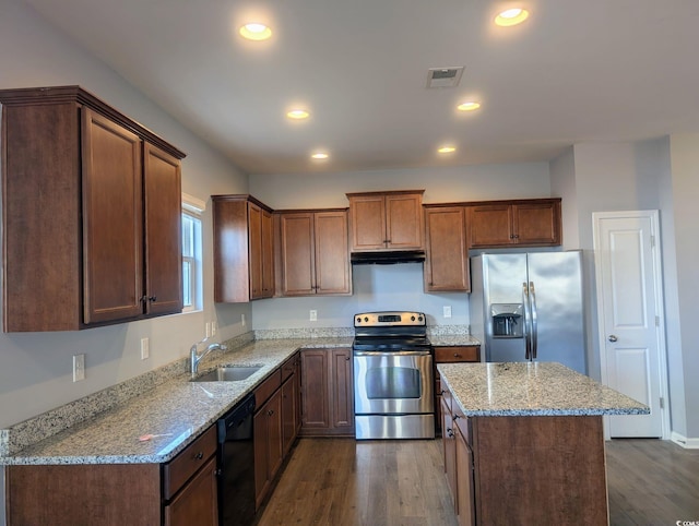 kitchen with appliances with stainless steel finishes, light stone counters, and hardwood / wood-style floors