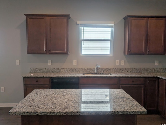 kitchen featuring light stone counters, sink, dishwasher, and dark brown cabinets