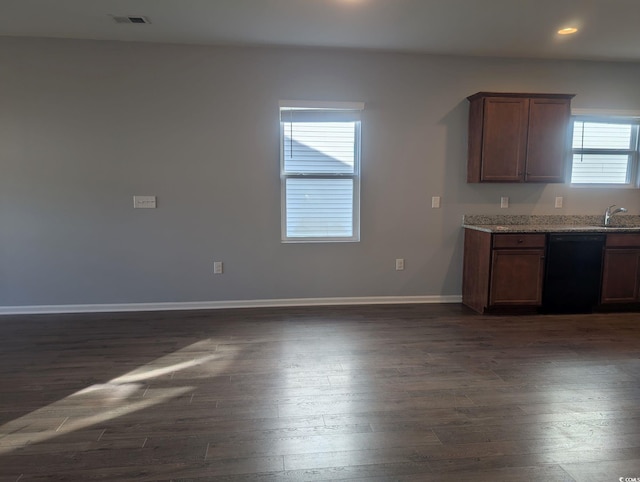 kitchen featuring light stone countertops, dark wood-type flooring, black dishwasher, and sink