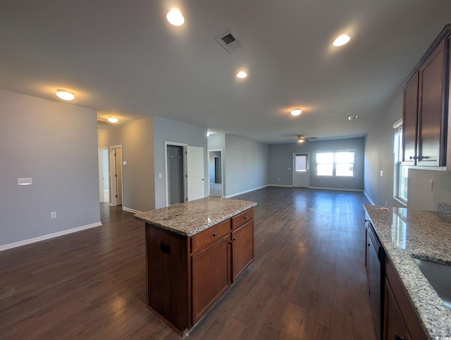 kitchen with ceiling fan, light stone counters, dark hardwood / wood-style flooring, and a kitchen island