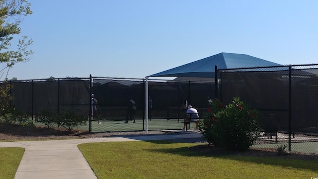 view of property's community featuring tennis court and a yard